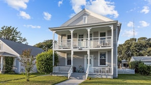 A two-story house with a front porch, a small front yard, and a clear blue sky. - A Seaside Serentiy in Morehead City (Morehead City)
