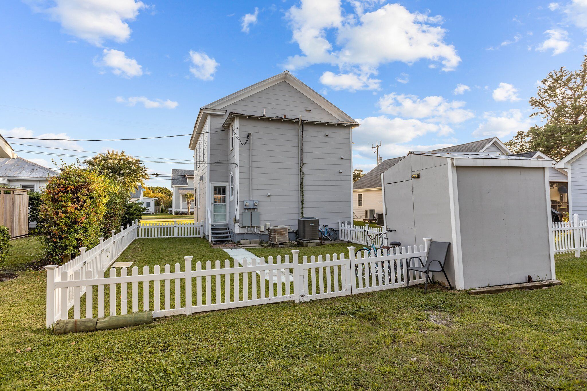 A single-story house with a white exterior, a small front yard, and a white picket fence.