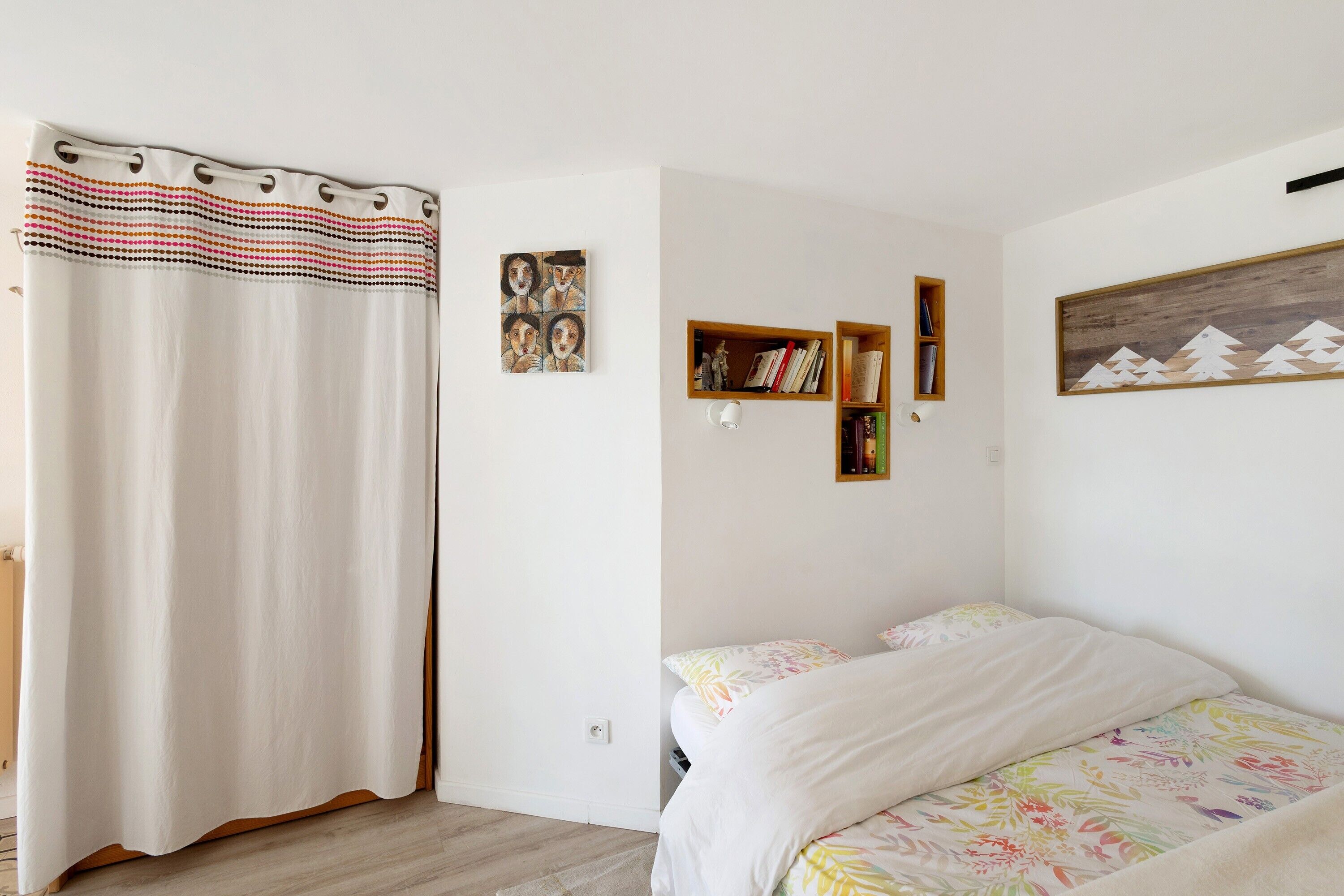 Une chambre à coucher avec un lit, une bibliothèque et un tableau accroché au mur.
