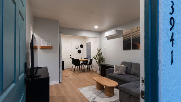 A modern living room with a sofa, coffee table, and a dining area with chairs and a table.