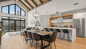 Une cuisine moderne dotée d’un îlot central, d’appareils électroménagers en acier inoxydable et d’une grande fenêtre donnant sur un paysage enneigé.
