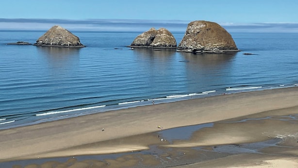 A beach with three large rock formations in the water and a sandy shore. - Surfers Perch: Amazing Pacific Ocean Views (Tillamook)