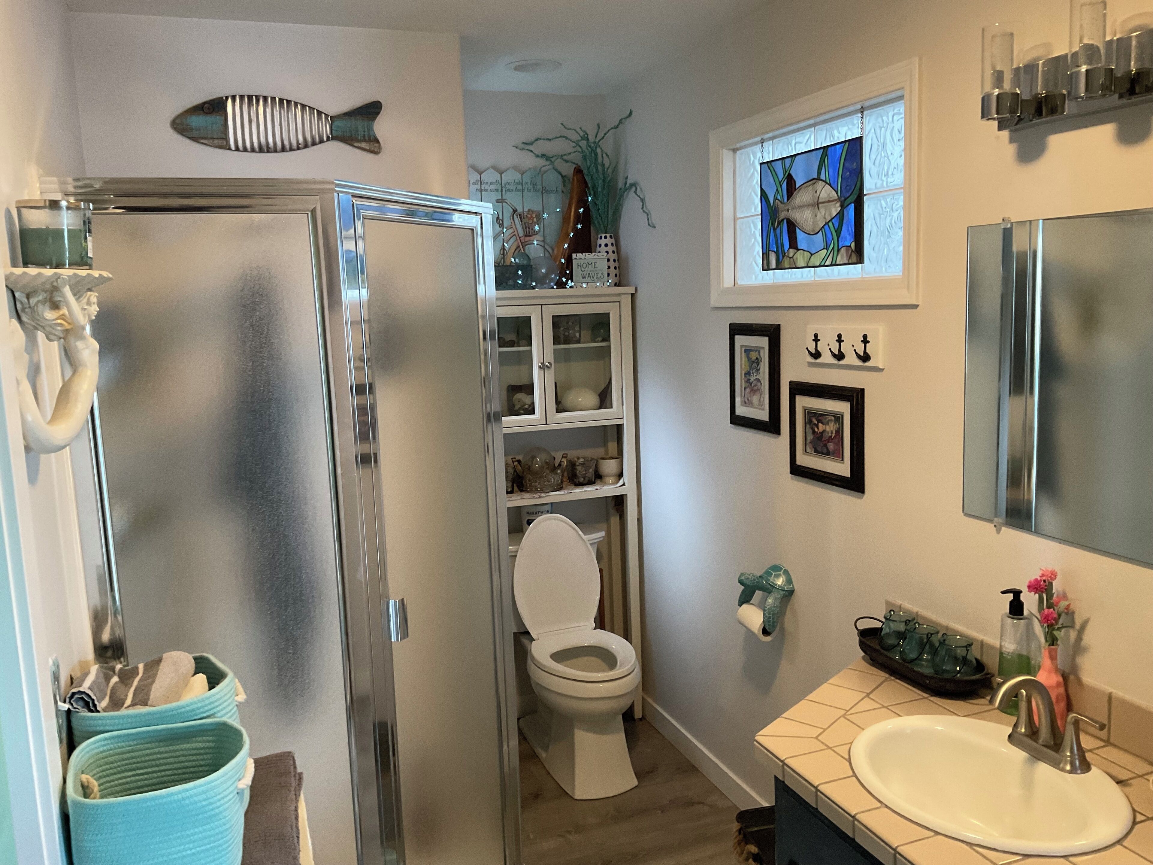A bathroom with a toilet, sink, and a fish-shaped decoration on the wall.
