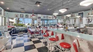A diner with a checkered floor, red bar stools, and a counter. - Chic Cozy Condo with Stunning Views (Daytona Beach Shores)
