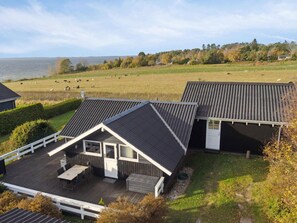 A house with a deck and a view of a field with cows.