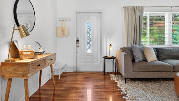 A living room with a wooden console table, a round mirror, a sofa, and a patterned rug. - 3 miles to Siesta Key, Screened in Lanai, 3 Bedrooms, Walking dist to Publix (Sarasota)
