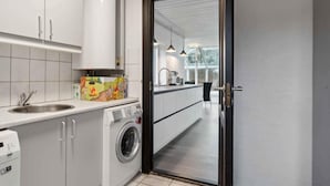 Eine moderne Küche mit Waschmaschine, Spüle und einem Fenster mit Blick auf einen Balkon.