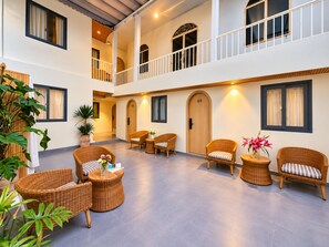 Un espace intérieur spacieux, aménagé avec des meubles en osier, des plantes en pot et un balcon doté de balustrades.