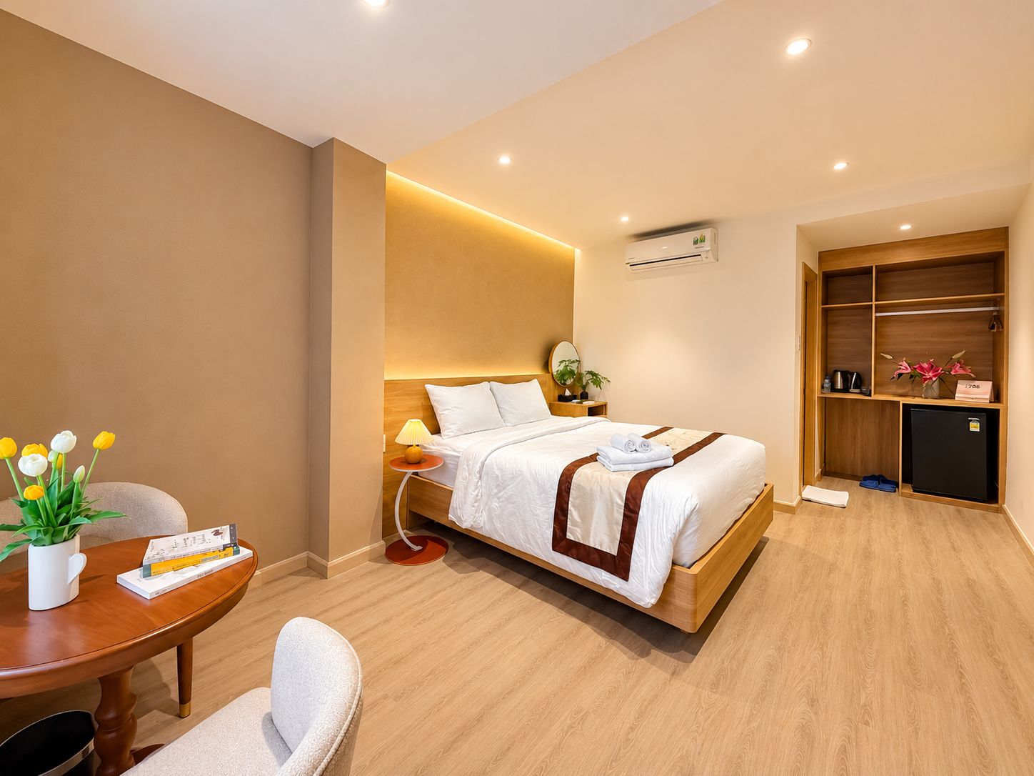 Habitación de hotel con cama, mesita de noche, lámpara y un escritorio pequeño con una silla.