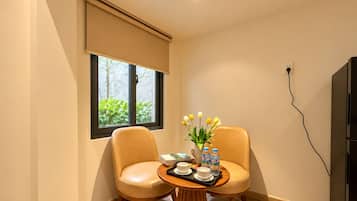 Una habitación con dos sillones de cuero, una mesita de madera con una bandeja de vasos y botellas de agua, y una ventana con vista a la vegetación.