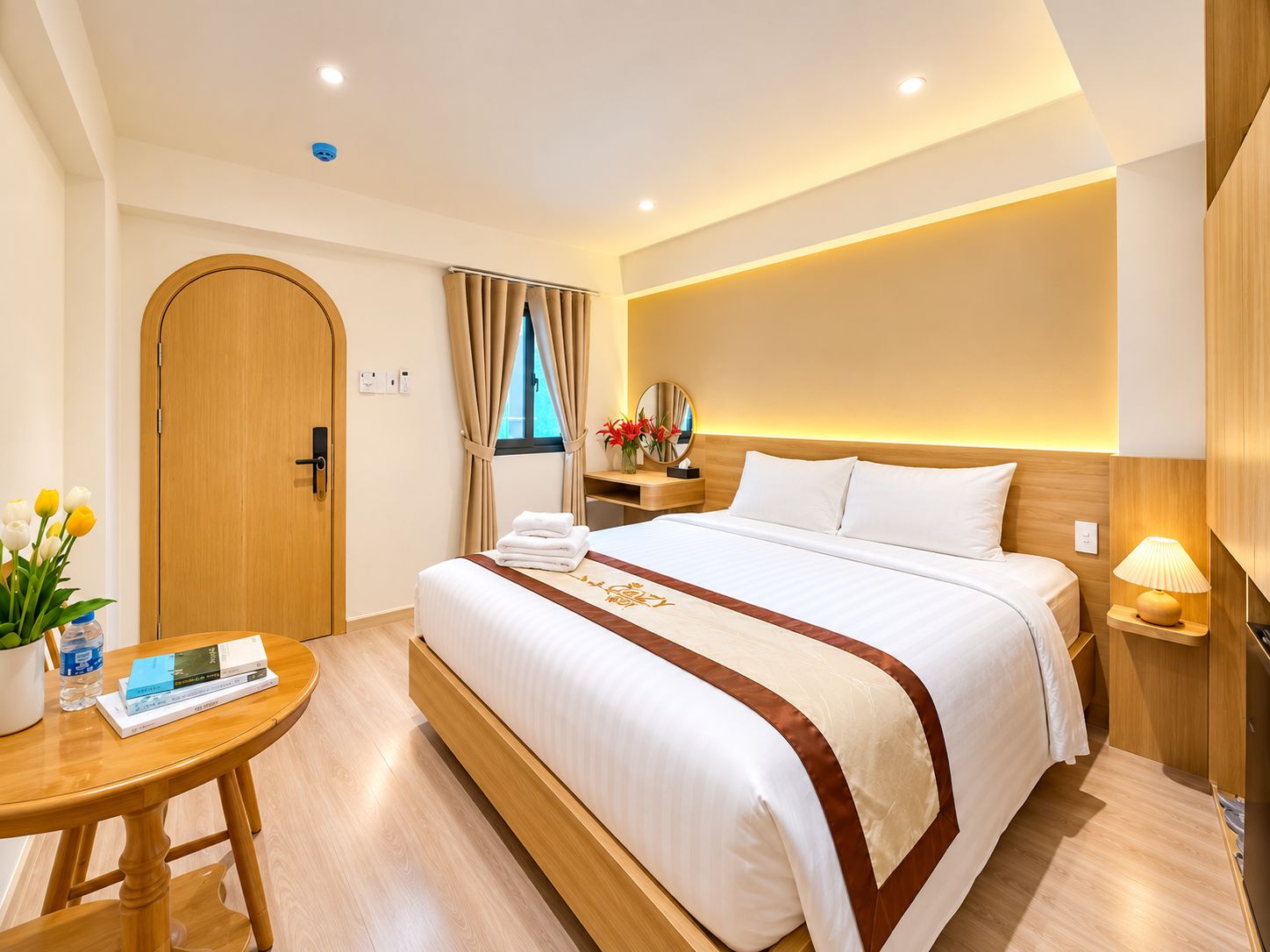Una habitación de hotel con cama, mesita de noche, lámpara y ventana con cortinas.