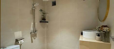 A modern bathroom with a shower, toilet, and sink.