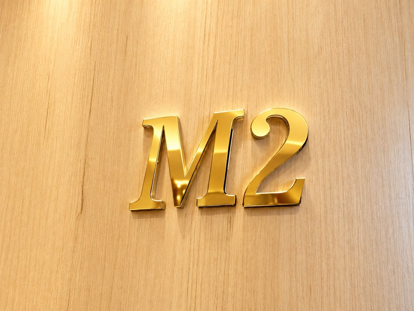 A wooden surface with the letters 'M2' in a shiny gold color.
