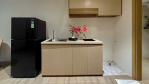 Une cuisine de taille réduite, avec un réfrigérateur noir, un évier et un meuble en bois placé au-dessus du plan de travail.