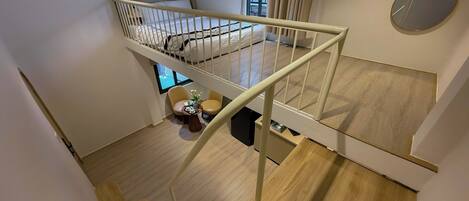 Un appartement moderne doté d’un escalier en bois, d’un lit superposé et d’un petit coin salon avec une table et des chaises.