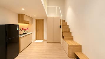 Una cocina moderna con refrigerador empotrado, armarios de madera y una escalera de madera que conduce a un altillo.