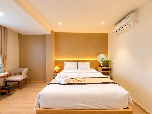 A hotel room with a bed, bedside table, lamp, chair, and an air conditioning unit. - Chinchu Stay (Ho Chi Minh City)