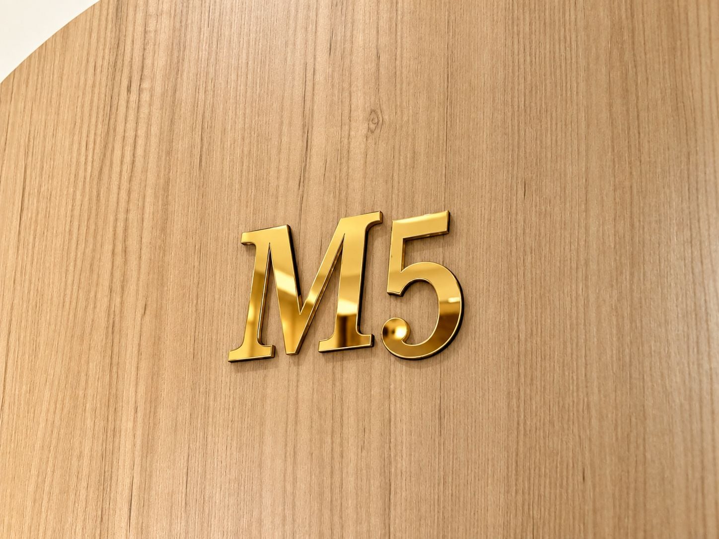 A wooden surface with the letters 'M5' embossed in a shiny gold material.