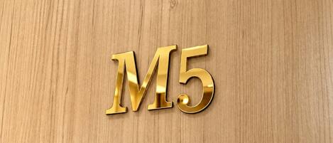 A wooden surface with the letters 'M5' embossed in a shiny gold material.