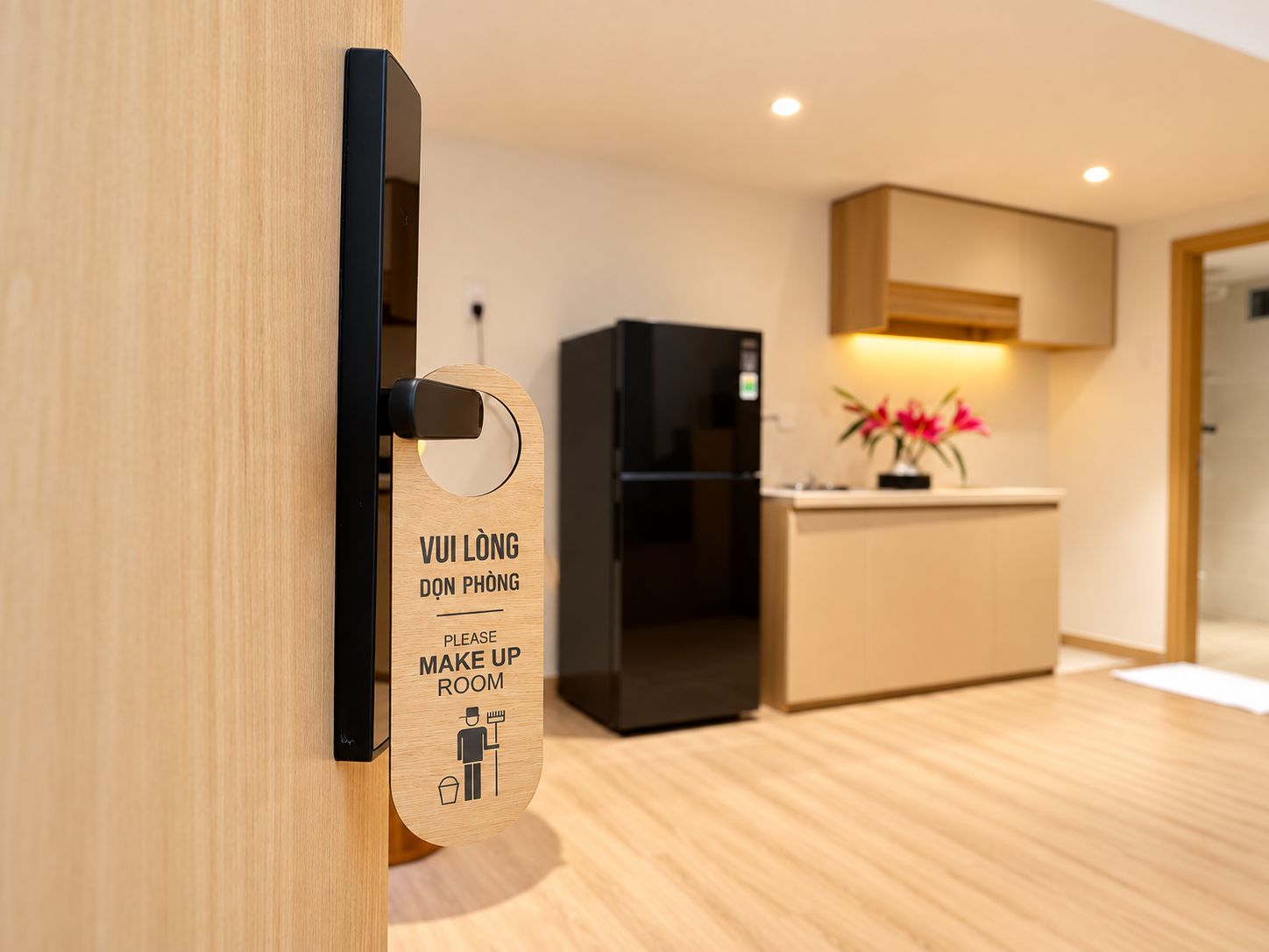 Una cocina moderna con un refrigerador negro, armarios de madera y un lavamanos.