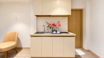 Una cocina compacta con un lavamanos integrado, una silla y una puerta de madera.