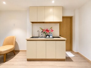 A compact kitchen with a built-in sink, a chair, and a wooden door.