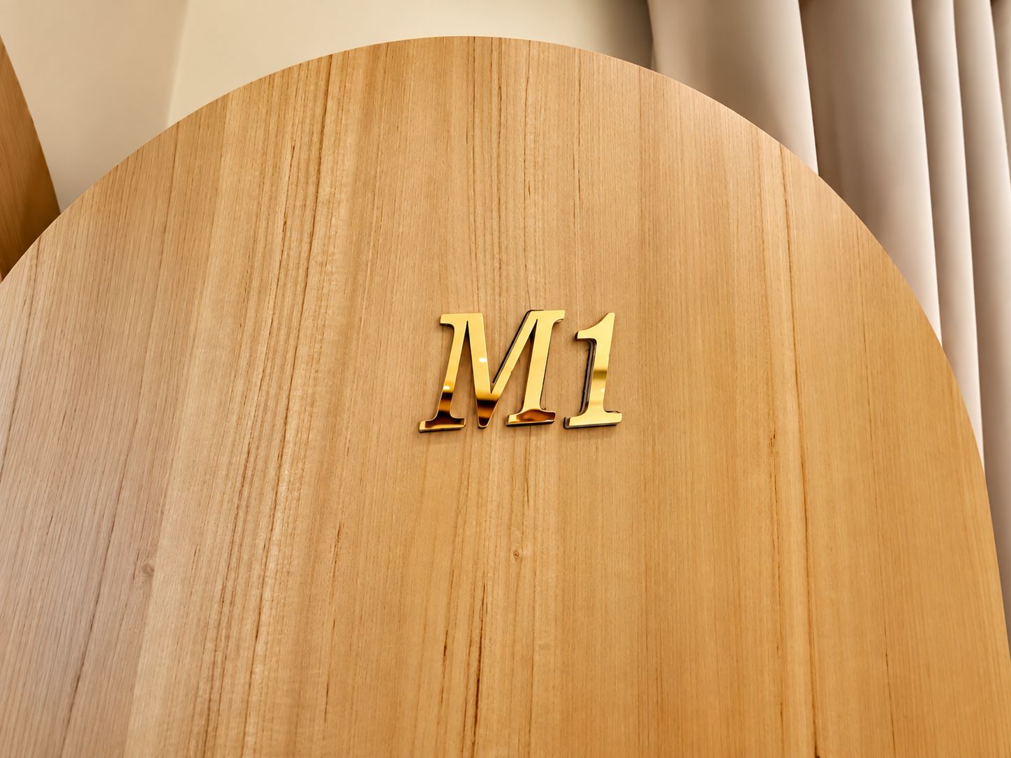 A circular wooden surface with the letters 'M1' in a metallic finish.