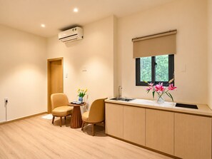 A compact kitchen with a window, a sink, and a small dining area with chairs. - Chinchu Stay  (Ho Chi Minh City)