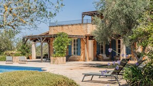 Une villa avec piscine, un espace salon extérieur et une pergola.