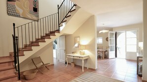 Ein geräumiger Wohnbereich mit Treppe, einem Esstisch und einem großen Fenster.