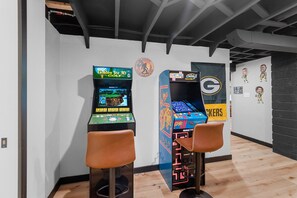 Two arcade machines, a wall with a logo, and a sign with 'Green Bay Packers' on a wall.
