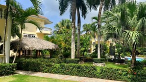 Un resort con piscina, palmeras y una estructura de techo de paja.