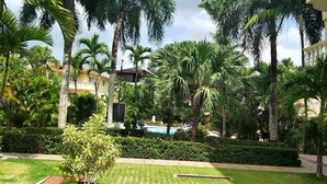 Un patio con palmeras, una piscina y un césped bien cuidado.