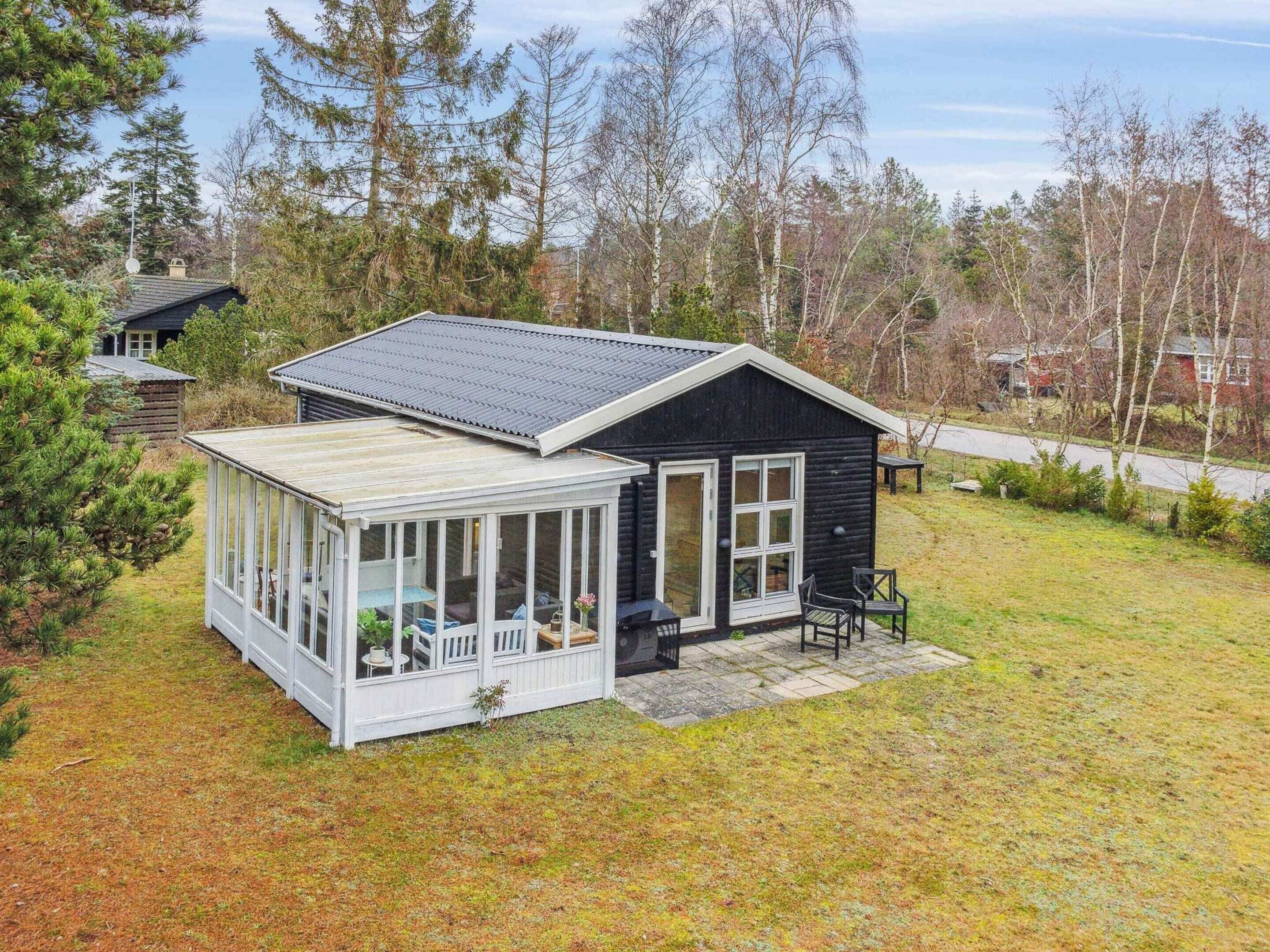 A small cabin with a covered porch and a separate glass room.