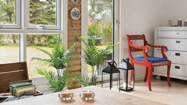 A room with a wooden desk, two potted plants, a red chair, and a white dresser. - 5 Star Holiday Home in Gedser (Gedser)