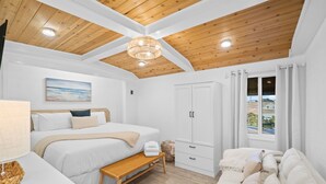 A bedroom with a wooden ceiling, a bed, a bench, a sofa, a wardrobe, and a window with curtains. - Gorgeous Updated Condo steps from beach - Unit A14 (Panama City Beach)