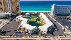 A hotel with a pool, parking lot, and ocean view. - Gorgeous Updated Condo steps from beach - Unit A14 (Panama City Beach)