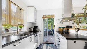 A modern kitchen with white cabinets, a black countertop, and a view to the outside. - 5 Star Holiday Home in Sjaellands Odde (Sjællands Odde)