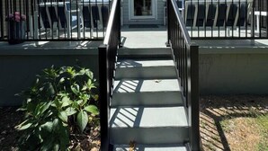 A house with a front porch, a staircase leading to the door, and a small garden area with plants. - Near Watts Bar | Pet-Friendly | 2 Kings | Easy Checkout (Rockwood)