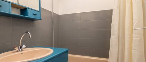 A bathroom with a sink, mirror, and shower.