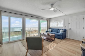 A spacious living room with a blue sofa, a wooden coffee table, and a ceiling fan.