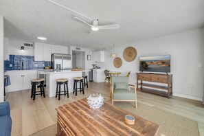 A modern kitchen with white cabinets, a central island, and bar stools.