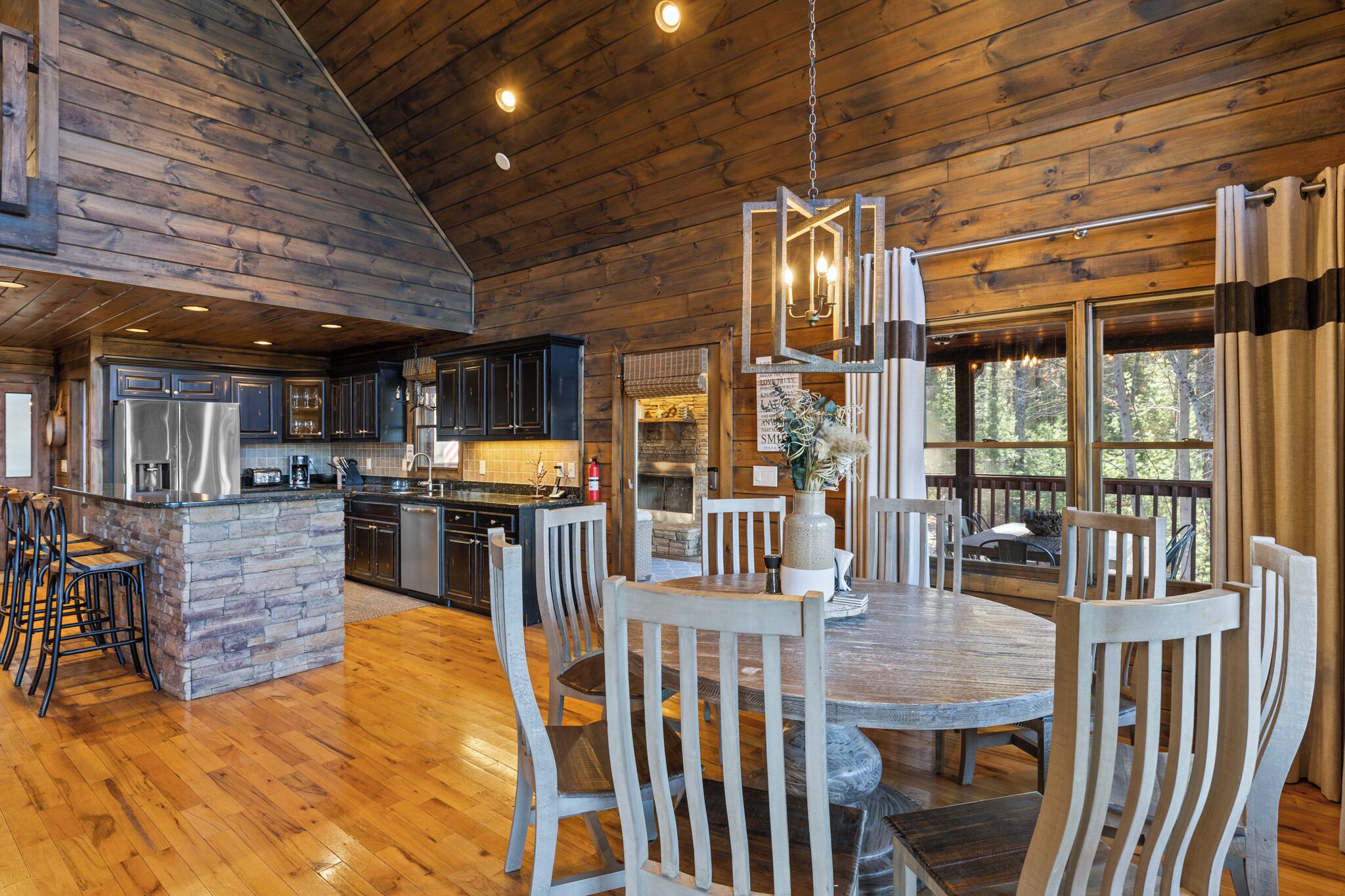 A spacious kitchen with a central island, wooden dining table, and chairs.