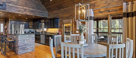 A spacious kitchen with a central island, wooden dining table, and chairs.