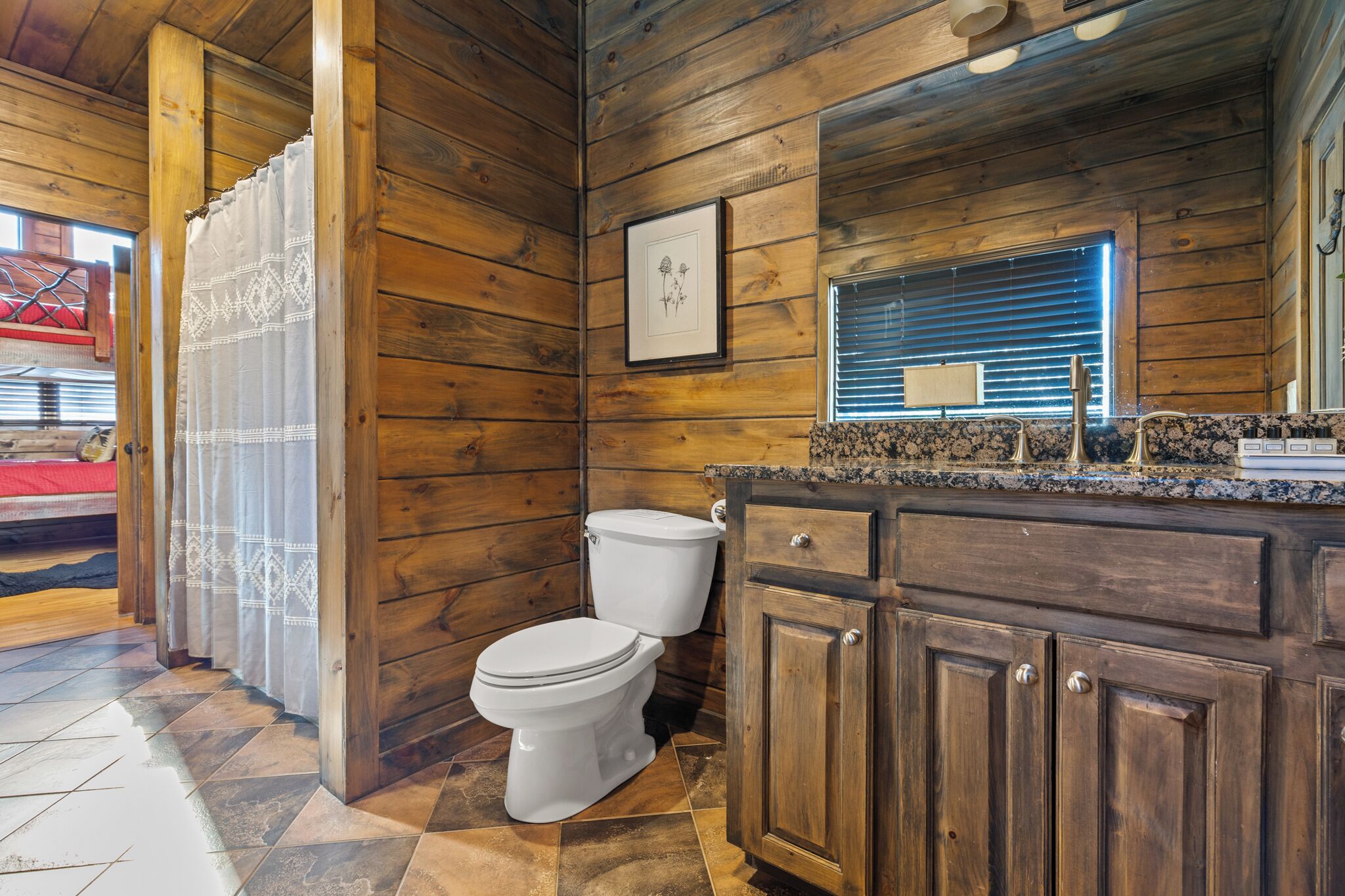 A wooden cabin bathroom with two toilets, a wooden vanity, and a framed picture on the wall.