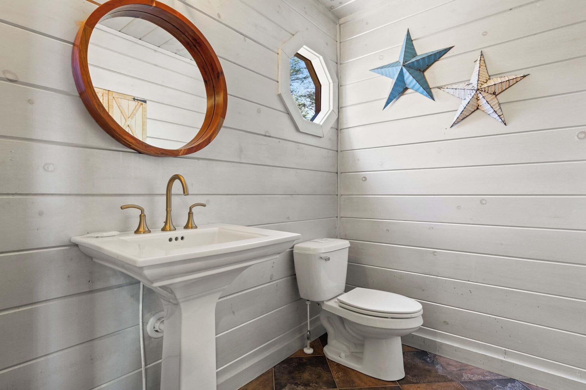 Een badkamer met een wit wastafelmeubel, een toilet en een spiegel. Twee ster decoraties sieren de wand.
