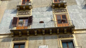 A building facade with ornate balconies, a plaque with text, and a sign indicating 5000 stores worldwide.