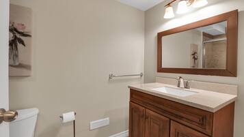 A bathroom with a beige wall, a wooden vanity with a sink, a mirror, and a towel rack.