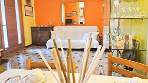 A room with a white sofa, a glass cabinet with wine glasses, a wooden cabinet, and a tiled floor. - Casa di Amelie By Case al Lago (Sirmione)