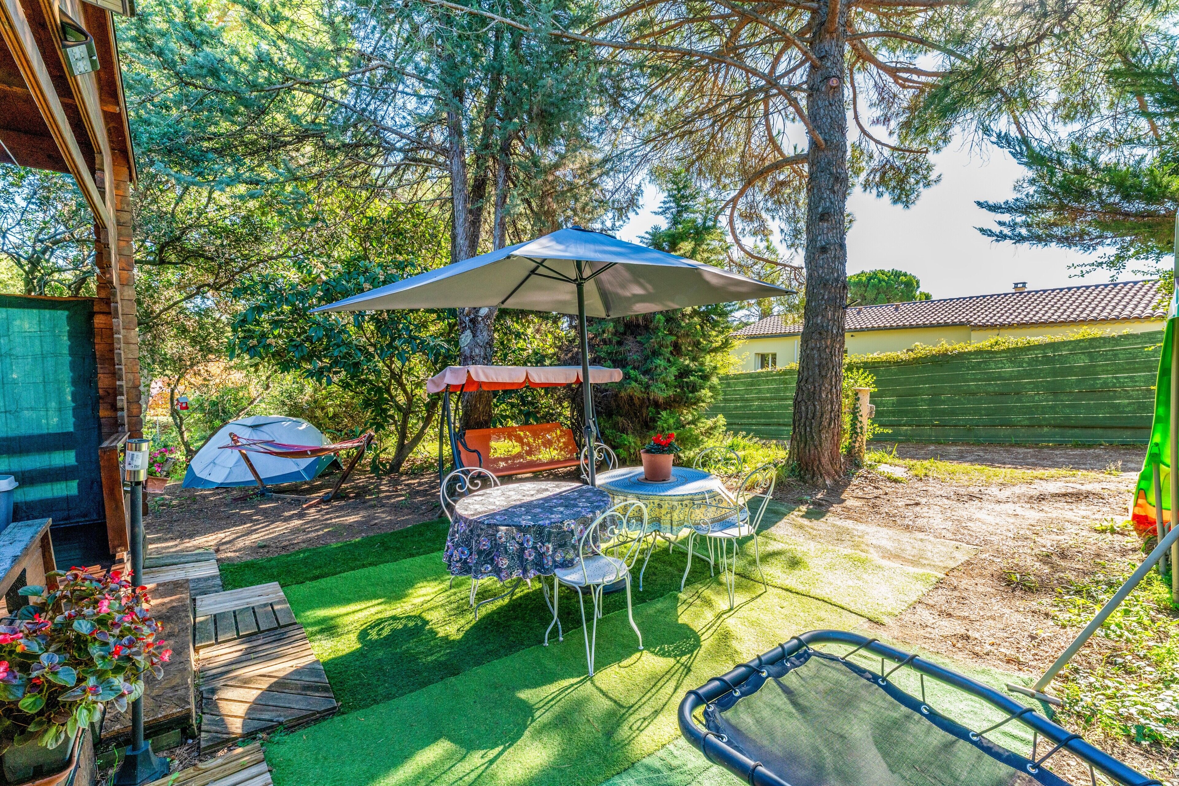 A patio with a table and chairs, a hammock, and a tent.